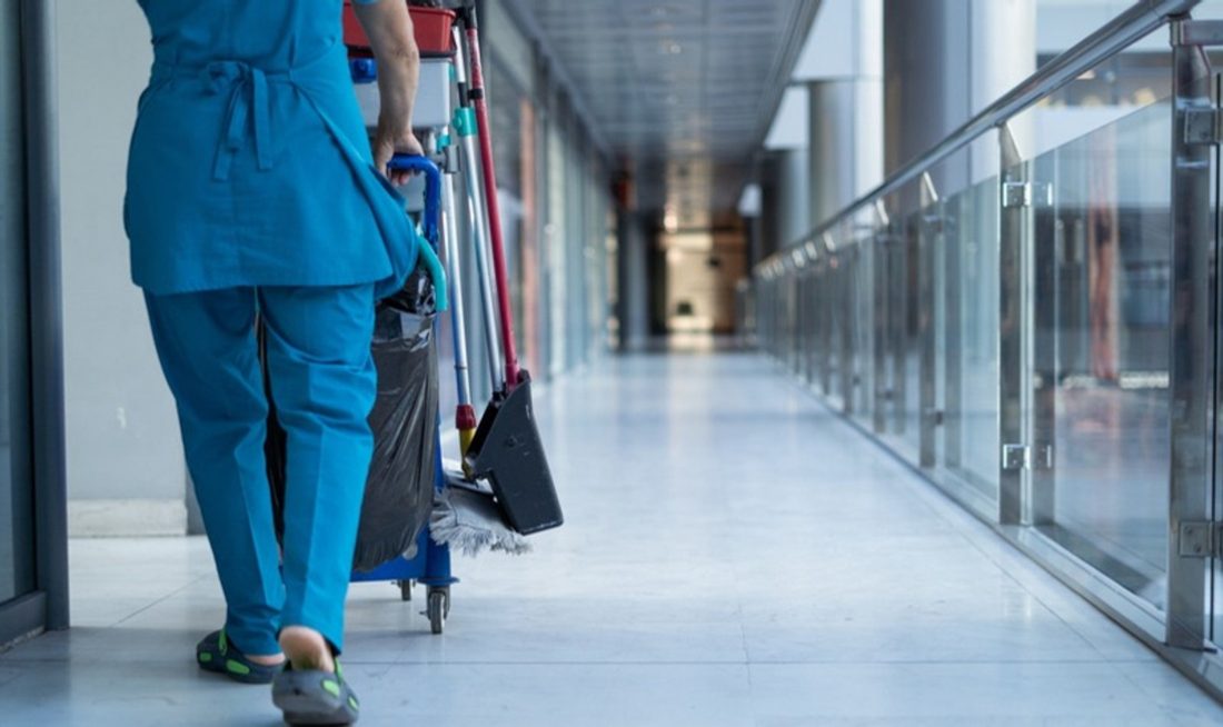 Janitorial crew member with a cleaning cart in a commercial building