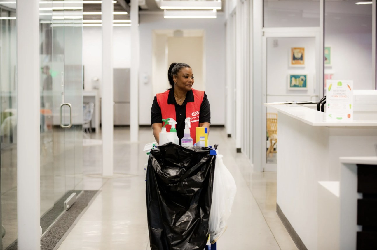 City Wide crew member pushing a cleaning cart through an office