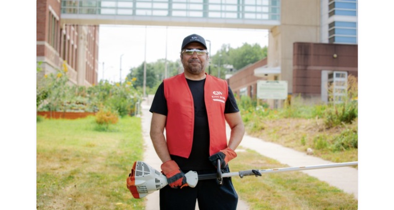 Landscaping vendor in a City Wide vest, smiling on a commercial property